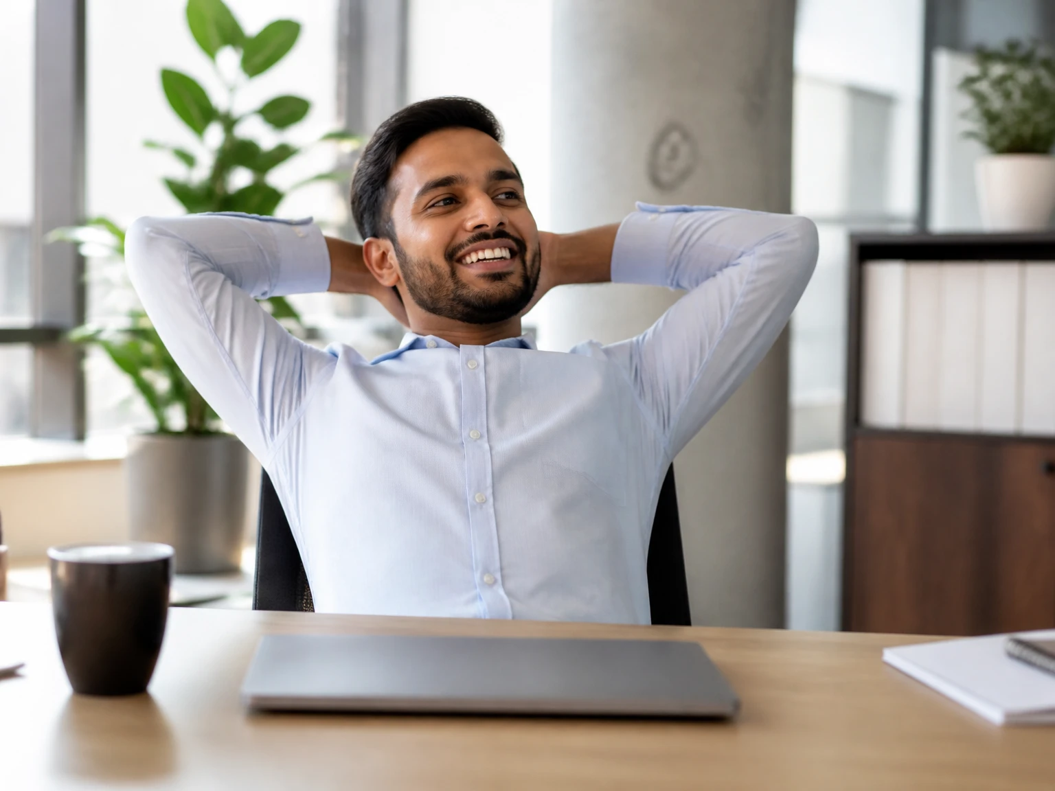 A relaxed office worker away from a tidy, closed laptop